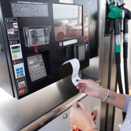 Cliente recoge un recibo en la gasolinera.