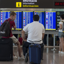 Varios viajeros consultan lo vuelos en los monitores del Aeropuerto de Barcelona-El Prat. EFE/Quique García