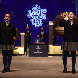 Paula Figuereo y Yanisse Alexandra, dos de las niñas de la residencia de San Ildefonso, posan minutos después de cantar el primer premio 86.148, durante la celebración del Sorteo Extraordinario de la Lotería de Navidad 2021 en el Teatro Real de Madrid