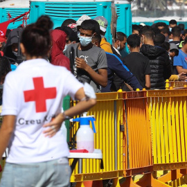 Una voluntaria de Cruz Roja junto a varios inmigrantes este jueves en el muelle de Arguineguín.