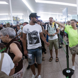 Miembros de la Asamblea Nacional de Cataluña (ANC) repartiendo folletos en el Aeropuerto de Barcelona-El Prat culpando al Estado de las colas que se han formado en las dos últimas semanas en los controles de seguridad del aeropuerto. EFE/Quique García