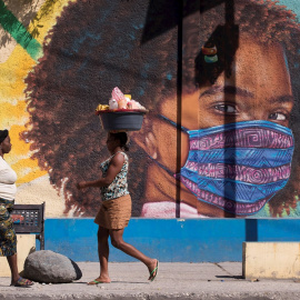 Dos mujeres caminan frente a un mural alusivo al uso del tapabocas por el coronavirus en Puerto Príncipe (Haití).