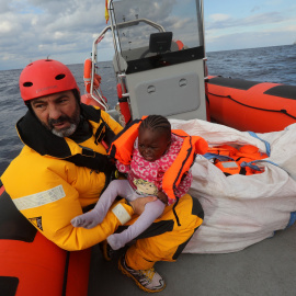 Un voluntario de Proactiva Open Arms rescata a un menor que iba junto a cientos de eprsonas en una bote hinchable en el Mediterráneo.- Una embarcación cargada de personas flota a la deriva en el Mediterráneo.- REUTERS/Yannis Behrakis