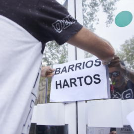 Un vecino coloca un cartel en la puerta de una oficina durante una protesta del colectivo Barrios Hartos. Imagen de archivo.