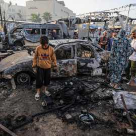 Palestinos inspeccionan coches quemados tras un ataque del ejército israelí contra tiendas para desplazados internos, a 14 de octubre de 2024.