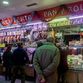 Varias personas esperan a ser atendidas en un puesto de productos alimentarios.