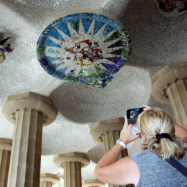 Una turista fotografia els medallons restaurats de la sala Hipòstila del Parc Güell.