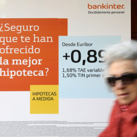 Una mujer pasa junto a una publicidad de hipotecas en una sucursal de Bankinter. REUTERS/Susana Vera