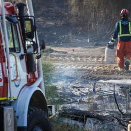 Un bombero trabaja en los restos de un incendio en un asentamiento chabolista de Lepe, en una imagen de archivo.