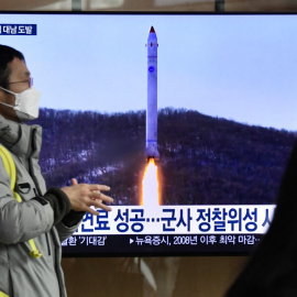 Un hombre frente a una televisión que muestra una transmisión de noticias con imágenes de archivo de una prueba de misiles de Corea del Norte el 31 de diciembre de 2022.