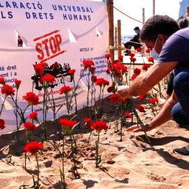 Un home plantant un clavell a la sorra de la platja. Imatge del 18 d'abril del 2021.