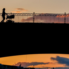 Una madre con un carrito de bebe paseando al atardecer por el Puente de Triana en Sevilla el 28 de abril del 2020.