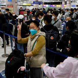 Una mujer celebra en una abarrotada estación de Lok Ma Chau, en Hong Kong, la reapertura de fronteras en China