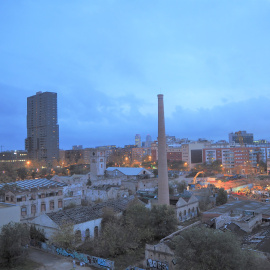 Las naves deterioradas de Can Ricart con su gran chimenea en pie, mientras a su alrededor se construyen oficinas y hoteles.