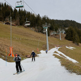 Esquiadores pasan sobre una pequeña capa de nieve en medio de temperaturas invernales más cálidas de lo habitual en los Alpes en Leysin, Suiza, a 4 de enero de 2023