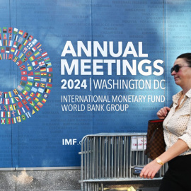 Una persona pasa junto a uno de los carteles que anuncia la Asamblea Anual del FMI y del Banco Mundial, en su sede en Washington. AFP/Mandel Ngan