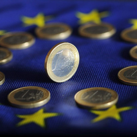 Monedas de euro sobre una bandera de la UE.