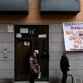 Varias personas pasan por la fachada del número 11 de la calle María Guerrero del madrileño barrio de Carabanchel donde hay un cartel contra la Sareb. Imagen de archivo.