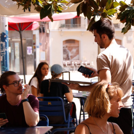 09/08/2024 - Un cambrer en una terrassa d'un bar de Gràcia, a Barcelona.