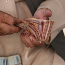 Un hombre cuenta efectivo en un mercado de cambio de dinero en Kabul, Afganistán