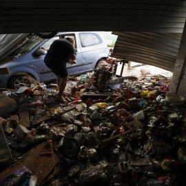 Una persona intenta recoger alimentos de una tienda en València, tras las fuertes lluvias causadas por la DANA