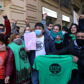 El Carlos, envoltat d'activistes pel dret a l'habitatge, mostrant el paper de suspensió del desnonament que l'afectava, aquest 3 de desembre de 2021.