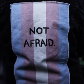 Imagen de archivo de una persona con un chaleco con una bandera trans en la espalda con las palabras "Sin miedo"