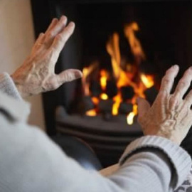 Una mujer calienta sus manos en una chimenea.