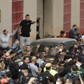 El rey Felipe (c) rodeado por vecinos indignados, durante su visita a Paiporta este domingo. Gritos de 'fuera', así como lanzamiento de barro, están recibiendo a la comitiva de los reyes de España, el presidente del Gobierno, Pedro Sánchez, y el presi