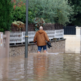 Un home caminant per un carrer inundat de la urbanització La Móra de Tarragona