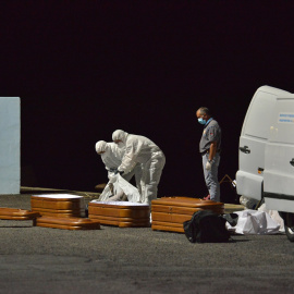 Varios trabajadores introducen en un ataúd a una persona fallecida en alta mar tras intentar llegar a la costa a bordo de una patera, a 11 de abril de 2021, en el puerto de la Restinga, Canarias.