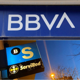 Los logos del BBVA y del Banco Sabadell en sendas oficinas bancarias.