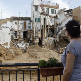 Una mujer observa varias casa dañadas por la Dana en Chiva, València,