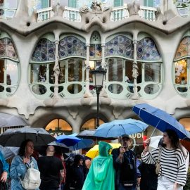 Persones es protegeixen de la pluja al passeig de Gràcia de Barcelona, en una imatge d'arxiu