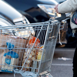 Una mujer sale de un supermercado con un carro de la compra, a 27 de diciembre de 2022, en Mejorada del Campo, Madrid.