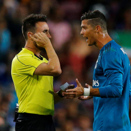 El jugador del Real Madrid Cristiano Ronaldo protesta ante el árbitro Ricardo de Burgos Bengoetxea por su expulsión en el partido de ida de la Supercopa de España en el Nou Camp. REUTERS/Juan Medina