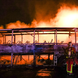 Los bomberos tratan de extinguir las llamas de un autobús durante la cuarta noche de disturbios por la muerte de un joven negro, en Nanterre a 1 de julio de 2023