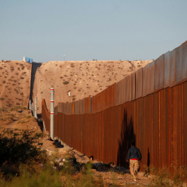 Un hombre pasa por una sección del muro que separa EEUU de México, cerca de Ciudad Juarez. - REUTERS