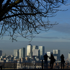 Varias personas toman fotos desde el Parque Greenwich de Canary Wharf, el distrito financiero londinense donde tienen su sede gran número de bancos internacionales y oficinas. AFP/Ben Stansall