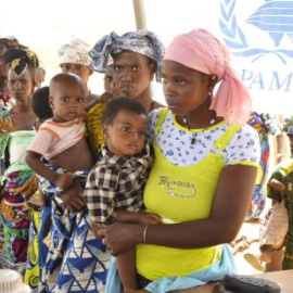 Mujeres y niños hacen cola en un campamento de Burkina Faso. AFP/Ahmed Oioba/Archivo