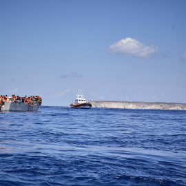 Foto de archivo, patera donde viajan migrantes y una patrullera de la Guardia Costera de Lampedusa