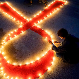 Una persona enciende velas formando una cinta roja por el día Mundial del SIDA, en una imagen de archivo del 30 de noviembre de 2020.