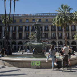 Uns joves descansen i parlen a la font de la plaça Reial