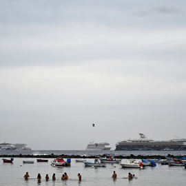 La gente disfruta de un baño mientras los cruceros están anclados en la playa de Los Cristianos, en la costa sur de la isla canaria de Tenerife, España, en el verano de 2021.