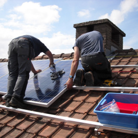 Dos instaladores colocan placas solares en el edificio de una vivienda, en una imagen de archivo