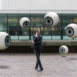 Una mujer es observada por varios ojos que flotan a su alrededor