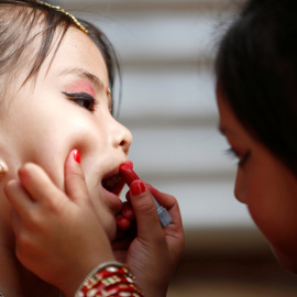 Una niña le pinta los labios a su amiga. REUTERS/ Navesh Chitrakar