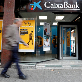 Un hombre pasa junto a una sucursal de Caixabank en Barcelona. REUTERS/Yves Herman