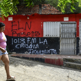 Una mujer pasa frente a una casa con un grafiti de la guerrilla del ELN cerca de Cacuta, Colombia, a 4 de julio.