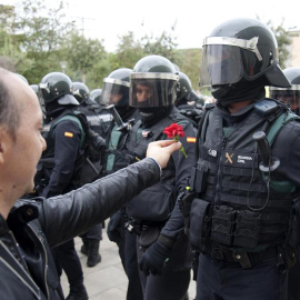 Un hombre ofrece un clavel a un agente de la Guardia Civil en el centro de votación de Sant Julià de Ramis (Girona) donde inicialmente tenía previsto votar el presidente de la Generalitat, Carles Puigdemont, en el referéndum independentista del 1-O./ 